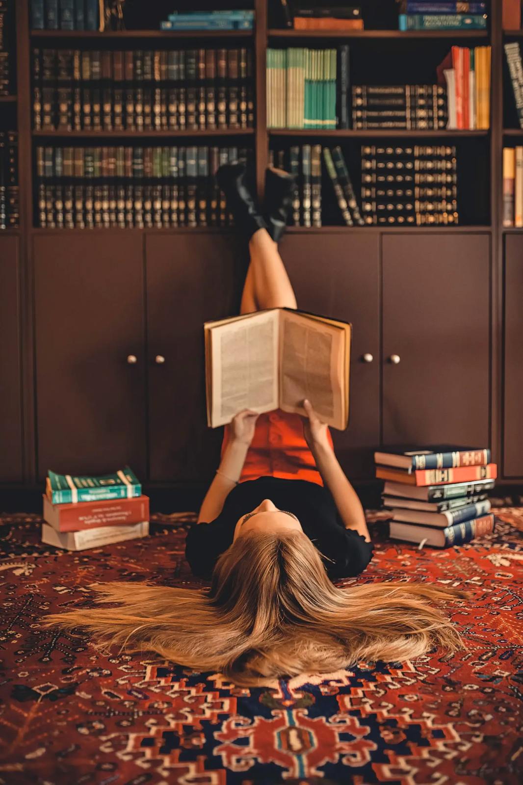 Girl reading a book while laying on a carpet
