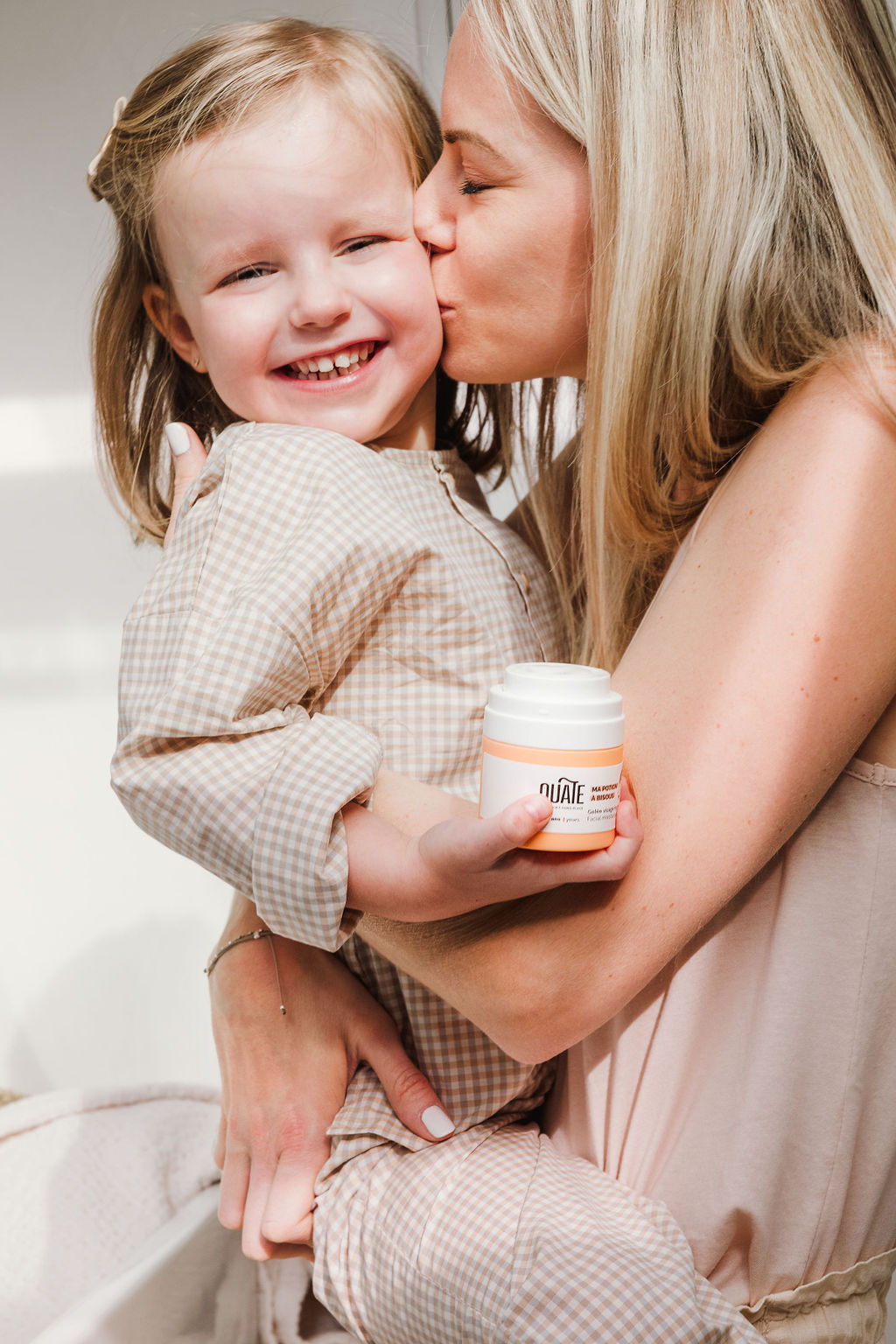 Mom kisses her daughter, OUATE children's products brand