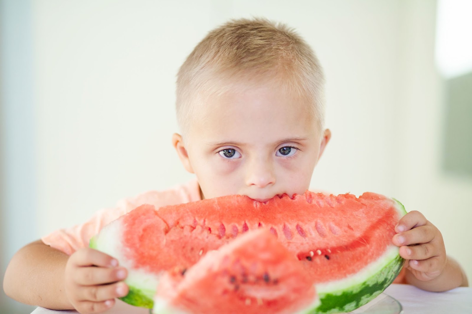Un niño con síndrome de down comiendo sandía