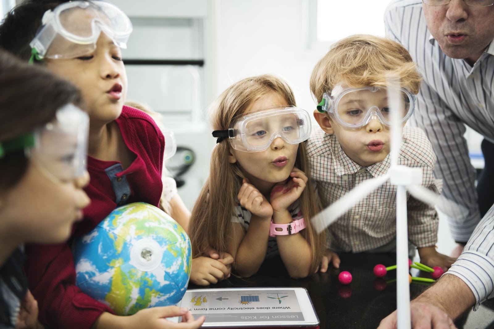Diversi studenti di scuola materna imparare produttore di energia dal mulino a vento solare in classe scientifica